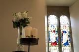a stained glass window and a decorative stand with candles and flowers