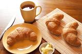 Continental breakfast with freshly baked croissants, butter and a mug of strong black filter or espresso coffee