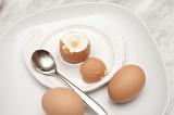 Boiled eggs for breakfast with a soft boiled egg in an egg cup served with two additional eggs on the side