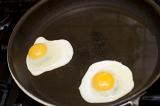 Two fried eggs with rich yellow yolks in a non-stick frying pan ready to serve for breakfast
