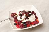Healthy fruit breakfast with a bowl of raisins, strawberries, raspberries and blueberries served with thick creamy yoghurt