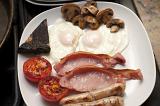 Full cooked English breakfast with fried eggs, bacon, sausages, mushrooms, tomato and black pudding served on a plate for a hearty meal