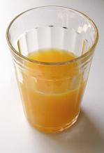 Glass half full of fresh healthy orange juice rich in vitamins for a refreshing breakfast beverage