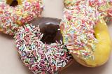 Assorted colorful doughnuts with orange, lemon and chocolate glazing dipped in multicolored sprinkles ready for a tasty snack during a morning coffee break