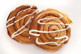 Two sweet Danish pastries with their traditional spiral shape filled with apple or almond and drizzled with icing, view from above on white