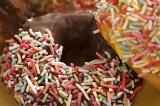 Closeup detail of a decorated ring doughnut glazed with chocolate and orange icing dipped in multicolored sprinkles
