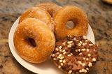 Plate of fresh golden sugared ring donuts with one glazed and decorated doughnut on the side , high angle closeup view
