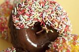 Glazed chocolate and lemon ring doughnuts or donuts covered in colorful candy sprinkles for a kids birthday party or coffee break