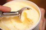 Man serving tasty creamy vanilla Ice cream in a bowl with a metal scoop, close up view