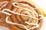 Close up of a traditional spiral apple or almond Danish pastry drizzled with icing