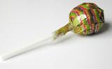 Wrapped round lollipop on a stick lying on a white background at a diagonal angle with the lollypop away from the camera, with copyspace