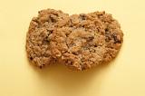 Overhead view of a pile of crunchy raisin cookies on a pale yellow background with copyspace
