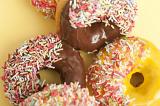 Orange and chocolate glazed ring doughnuts or donuts dipped in multicolored sprinkles for a tasty coffee break or dessert