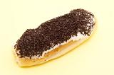 Freshly baked sticky bun covered in tasty chocolate sprinkles, high angle view on yellow with copyspace