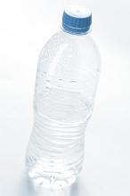 Plastic bottle of cold fresh pure mineral water with beaded condensation on the surface and a blue cap, unlabeled on white