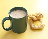 Mug of frothy cappuccino coffee with two cookies for a relaxing coffee break on a yellow background