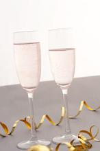 Celebrating with two elegant flutes of sparkling pink champagne with twirled gold party streamers for a special romantic occasion
