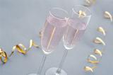 Romantic celebrations with two elegant flutes of pink champagne and twirled golden party streamers, high angle closeup view
