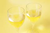 Two glasses of white chardonnay wine viewed high angle closeup over a yellow background