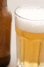 Glass of beer, lager or draft with a good frothy head alongside a brown beer bottle