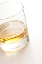 Glass of neat golden malt whiskey served straight conceptual of relaxation, a bar or pub, viewed at a tilted angle on white