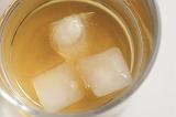 Iced tot measure of whiskey on the rocks in a glass tumbler, close up view of the beverage and ice cubes from above