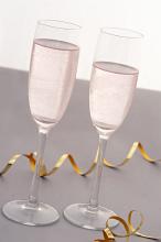 Two elegant flutes of sparkling pink party champagne to celebrate a festive or romantic occasion with a coiled gold decorative streamer