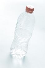 Pure water in an unlabeled closed plastic bottle, tilted high angle view on white