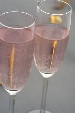 Two elegant flutes or long stemmed glasses of bubbly effervescent rose or pink champagne for a holiday or romantic celebration