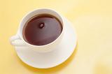 Freshly brewed cup of hot black tea for a relaxing tea break viewed high angle on a yellow background with copyspace