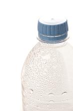 Close up of a plastic bottle of refreshing chilled water with condensation droplets on the exterior surface over white with copyspace