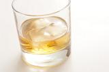 Whiskey on the rocks served with ice cubes in a traditional glass tumbler, close up view on white