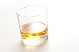 Glass of neat whiskey served straight on a white background with copyspace