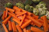 Chopped fresh carrots and broccoli on a counter in a kitchen ready to be cooked for dinner , closeup background view