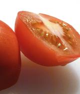 Fresh halved juicy red tomato dripping juice ready to be used in a healthy salad or as a cooking ingredient in a recipe