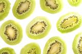 Background texture and pattern of thin slices of fresh peeled tropical kiwifruit arranged on a white background