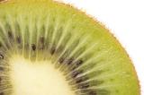 Macro detail of a cut fresh kiwifruit showing the succulent green flesh and rayed pattern of the pips isolated on white