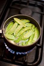 Gourmet mangetout or sugar snap peas cooking in a pot on a gas hob, high angle view