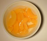 Bowl of canned peach segments in syrup served for dessert, overhead view