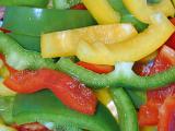 Food or catering background of sliced colorful sweet bell peppers in green, red and orange for use in a healthy fresh salad or as a flavoring in cooking