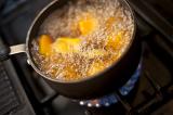 Pumpkin pieces boiling in a saucepan on a gas ring on the hob with lots of frothy bubbles, high angle view