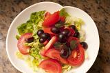 Fresh tomato salad on a plate with leafy green lettuce and fresh grapes for a healthy appetizer or accompaniment to a meal
