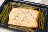 Portion of delicious gourmet oven baked salmon and green asparagus spears in a baking tray straight from the oven for healthy seafood cuisine
