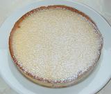 Baked pie in a crispy pastry crust sprinkled with icing sugar and served on a white plate, high angle view