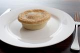 Freshly baked pie on a plain white plate with a closed pastry crust and no accompaniments