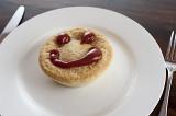 Meat pie with a happy face made of tasty sauce on top of the pastry crust served on a plain white plate