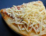 Slice of uncooked Italian pizza with a pastry base topped with tomato paste and grated cheese