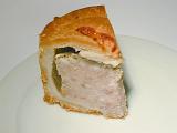 Slice of traditional English cold pork pie showing the texture of the meat and jelly in a flaky pastry case