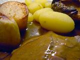 Close up of a serving of traditional English sliced roast beef, potato and Yorkshire Pudding topped with gravy