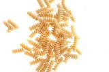 Spiral twist uncooked dried Italian pasta scattered on a white background with copyspace viewed from above
